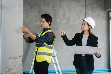 Asian male and female engineers wearing safety vests and helmets inspect structural elements,...