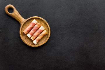 Spanish food. Prosciutto - rolls of ham on wooden cutting board, top view.