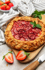 Delicious homemade strawberry galette decorated with almond petals and fresh mint