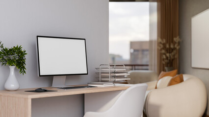 White screen computer and paper tray on wooden table with chair beside white wall of a living room.