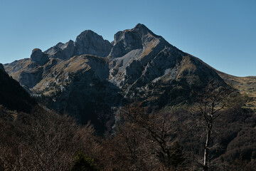 Dramatic rocky peak of Komovi mountain range in Montenegro under a clear blue sky. Majestic and rugged alpine scenery captured in crisp autumn light.
