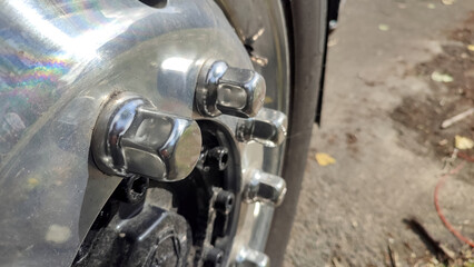 Close-up of a shiny chrome truck wheel with visible lug nuts and metallic reflections, taken...