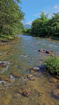 Drone flying low over Rio Maimon river, Bonao in Dominican Republic. Aerial, Vertical format