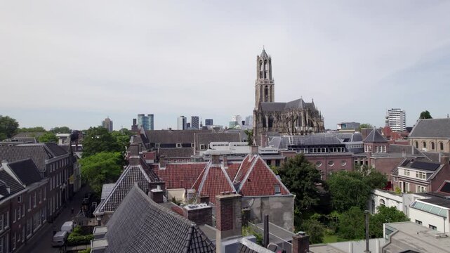 Rooftops of city center with De Dom church tower and the gothic architecture of the Utrecht diocese rising above. Holland religious tourist destination with modern buildings in the background.
