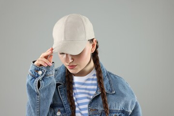 Woman in stylish baseball hat on grey background