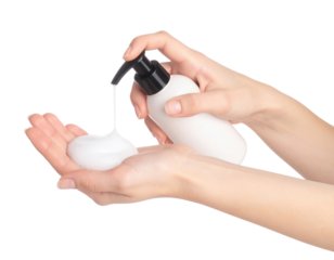 Liquid soap is being dispensed from a pump bottle onto a hand holding foam.