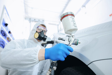Worker painting car in body shop, selective focus