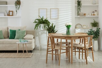 Comfortable sofa, table, chairs and green houseplants indoors. Interior design
