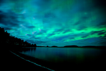 Moon light lake with a dancing northern lights in Farnebofjarden national park in north of Sweden.