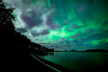 Moon light lake with a dancing northern lights in Farnebofjarden national park in north of Sweden.