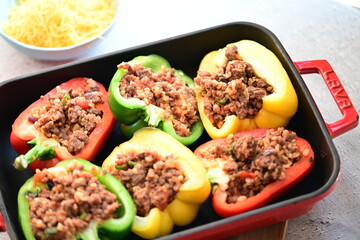 Close-up of colorful bell peppers stuffed with seasoned ground beef, ready for baking. A vibrant and appetizing preparation scene showcasing a classic homemade dish