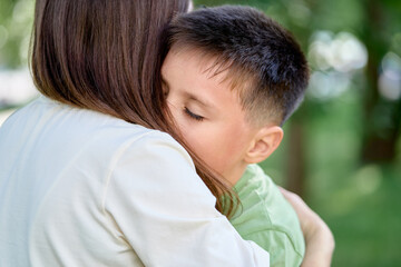 Obraz premium Mother and Son Sharing a Heartfelt Hug Outdoors in the Park