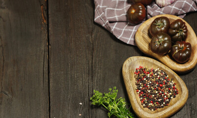 Black tomatoes and different spices on wooden table