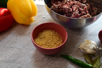 Bowl with cooking ingredients including bulgur, ready for meal preparation. A healthy, plant-based setup on a neutral background