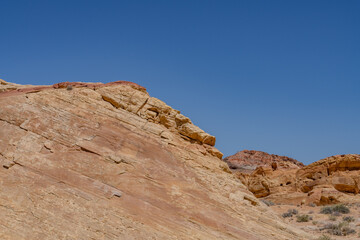 Fototapeta premium Fire Wave Trail, red Aztec Sandstone outcrops, Early Jurassic geological formation of primarily eolian sand. Valley of Fire State Park, Clark County, Nevada geology. Weathering. Desert varnish