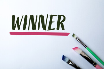 Winner Concept with Colorful Paintbrushes and Handwritten Text on White Background