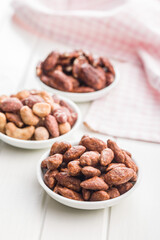 Almond nuts coated in sugar and honey in bowl on white table.