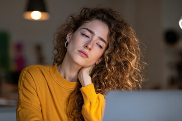 Young woman working laptop neck strain forward posture tired expression indoor natural light, Selective Focus..