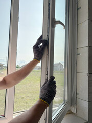A worker adjusts a plastic window in a new country house. Installing plastic windows in a new building.