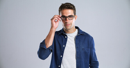 Man, glasses and portrait in studio for optometry, vision or adjusting to new lens for sight. Person, prescription specs or touch on white background space for eye care, designer frames or healthcare