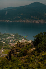 Man Sitting on Scenic Cliff by Cross and Italian Flag Overlooking Lake Iseo