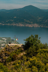 Man Sitting on Scenic Cliff by Cross and Italian Flag Overlooking Lake Iseo