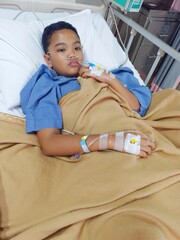 A teenage boy who is sick with weakness is being treated at the hospital, he has IVs in his hands.