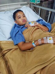 A teenage boy who is sick with weakness is being treated at the hospital, he has IVs in his hands.