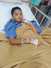 A teenage boy who is sick with weakness is being treated at the hospital, he has IVs in his hands.