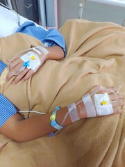 Two hands of a teenage boy being installed with an IV who is being treated in hospital, close up view