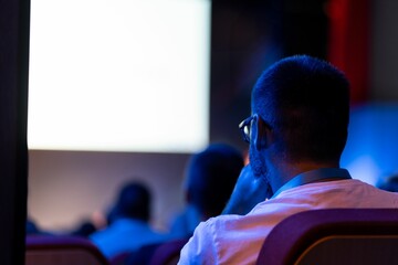 Audience member watches presentation in dimly lit auditorium during educational event