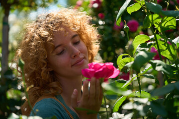 Gardener smelling a pink rose in a rose garden during summer