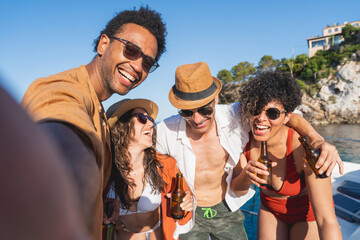 Friends taking a selfie and laughing while enjoying drinks on a boat - Group of friends smiling and drinking beer while taking a selfie. Summer, vacation, boat concept



