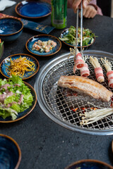 A person is currently cooking meat on a grill in a busy restaurant