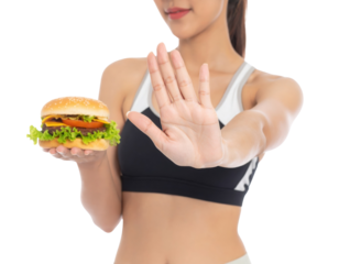 Athletic woman refusing a hamburger with a hand gesture, symbolizing healthy lifestyle choices.