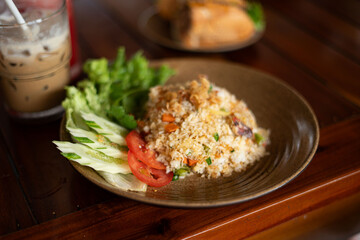 A plate of fried rice with tomatoes and lettuce on a table