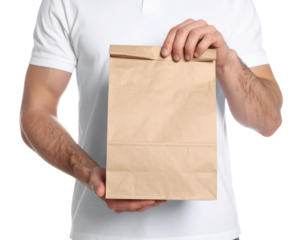 A person holds a plain brown paper bag with both hands, presenting it forward.