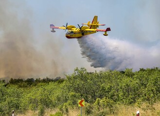 Aerial firefighting plane releasing water over a forest fire.