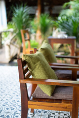 There is a wooden chair that has a soft green pillow resting on it