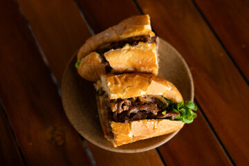 On a wooden table, there are two delicious sandwiches placed on a plate