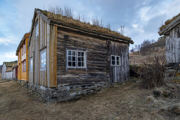 Norwegian old village on the fjord on the island of Kvaløya. open-air museum, old houses, landscape on the shore of Atlantic. steep snowy mountain on the roadside. We travel through Troms, Norway