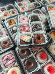 A delightful assortment of donuts, each adorned with colorful sprinkles, creamy frosting, and tempting chocolate glaze