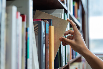 right hand choosing and picking book in public library.