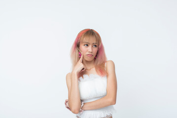 Young Southeast Asian woman with hand on cheek and a doubtful expression, dressed in soft Harajuku fashion. Isolated on a light background.