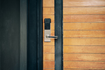 smart digital door lock on closed wooden door with dark grey concrete wall , modern lifestyle concepts