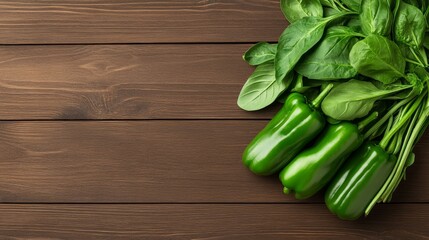 Fresh green bell peppers and basil leaves arranged on a wooden surface with copyspace for text