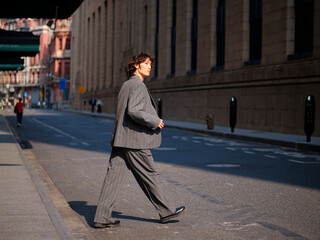 Portrait of handsome Chinese young man wearing gray suit walking in the street, young guy with black curly hair with urban background. Male fashion, cool Asian young man lifestyle.