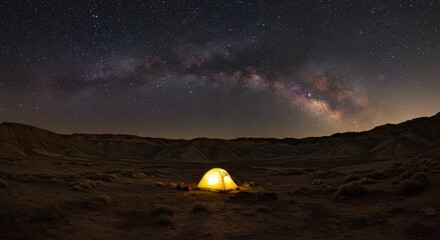 Obraz premium Glowing tent under a starry sky in a desert mountain landscape with the Milky Way visible above