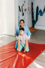 Physiotherapist assisting child with cerebral palsy in maintaining trunk control during quadrupedal position exercise