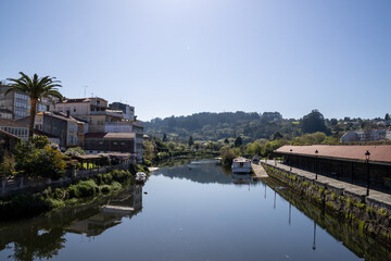 Obraz premium Scenic view of Ponte Vella bridge over Mandeo River in Betanzos, Galicia, Spain, surrounded by lush greenery and historic architecture.